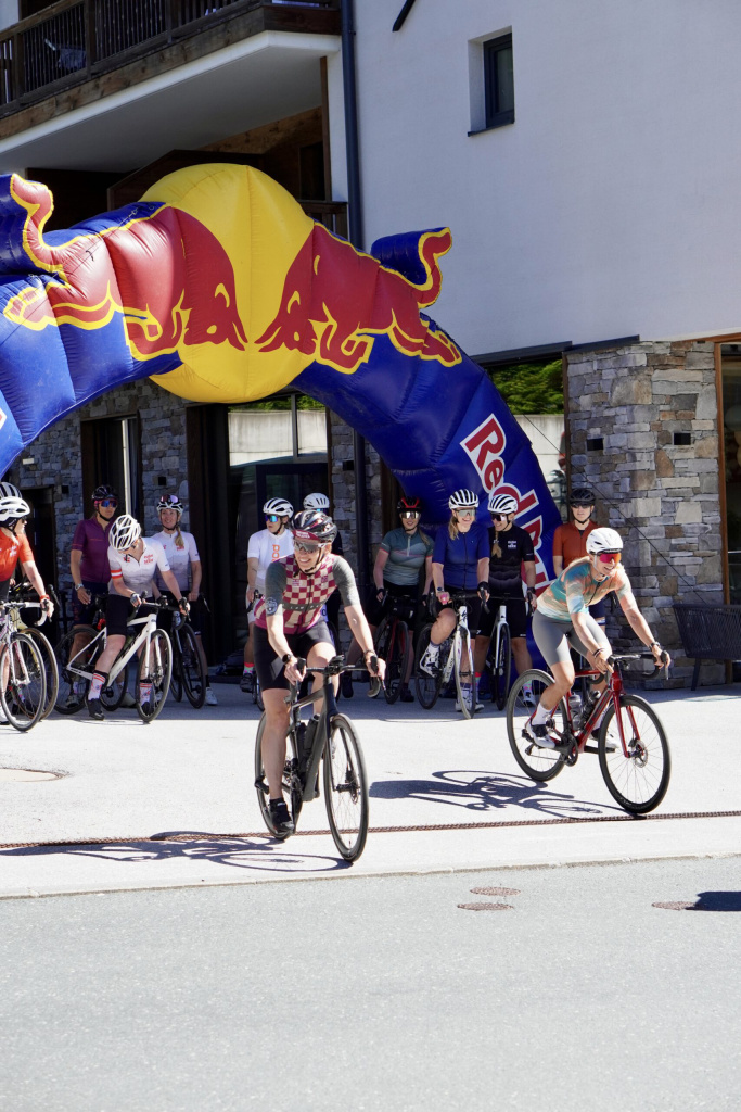 Rennradfahrerin in bunter Ausrüstung fährt entspannt durch grüne Berglandschaft im Oberpinzgau